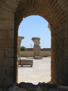 an arch in the side of a building with stone pillars and benches on either side