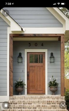 the front door of a house with two planters on it's side steps