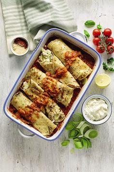 a casserole dish filled with meat and vegetables next to some sauces on the side