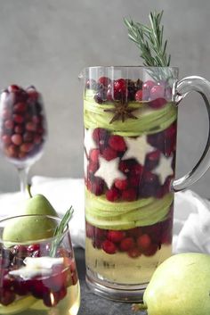 a pitcher filled with liquid and fruit next to two pears, an apple and rosemary sprigs