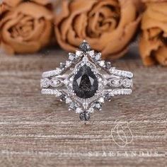 a diamond ring sitting on top of a wooden table next to some rose petals and flowers