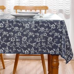 a blue table cloth with white flowers on it and a bowl sitting on top of the table