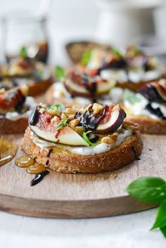 an open face sandwich with figs and other toppings on a wooden board next to some glasses