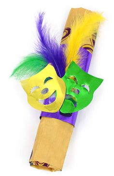 a mardi gras mask on top of a purple tube with yellow and green feathers