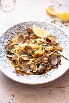 a plate of pasta with clams and lemon wedges