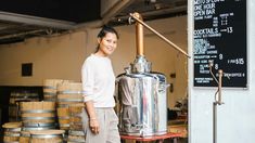 a woman standing in front of a large metal pot on top of a table next to barrels