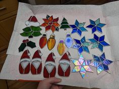 a person holding up a piece of paper with stained glass designs on it and other items