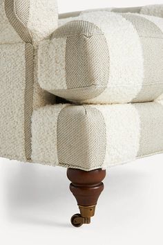 an upholstered chair with wooden feet and arm rests on a white background,