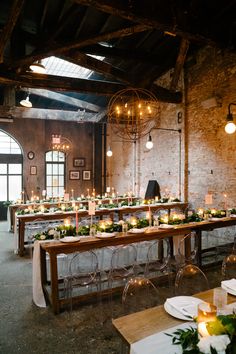 a long table with candles and greenery in front of an arched window at the end