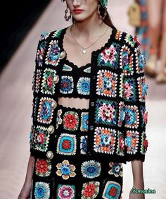 a model walks down the runway in a black crochet top with colorful flowers on it