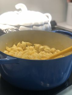 a blue pot filled with macaroni and cheese on top of a stovetop