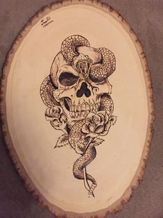 a wooden plate with a skull and snake on it's face, decorated with roses