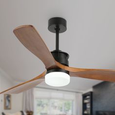 a ceiling fan in a living room with a light on it's side and wood blades