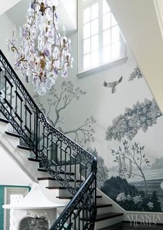 the staircase is decorated with wallpaper and a chandelier hanging from it's handrail