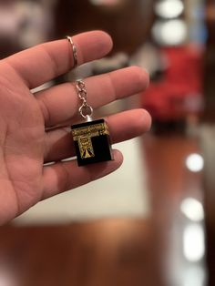 a hand holding a small black and gold keychain with an egyptian cross on it