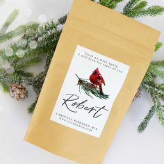 a brown bag with a cardinal on it sitting next to pine cones and evergreen branches