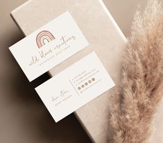 two business cards sitting on top of a white box next to a brown furry animal