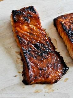 two pieces of grilled meat sitting on top of a cutting board next to each other