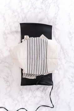 the black and white striped bag is on top of a marble countertop, next to an electric charger