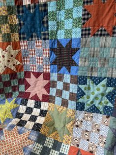 a close up of a quilt with many different colors and shapes on it, as well as stars