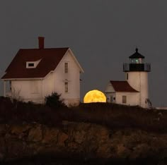 the moon is setting behind two white lighthouses