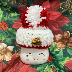 a small white cup with a red and white knitted hat on top