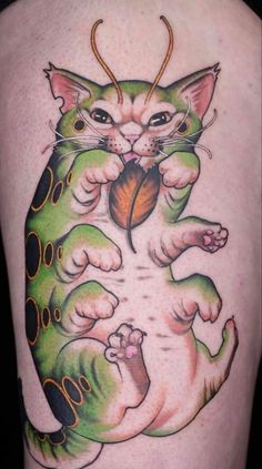 a cat tattoo on the back of a woman's leg, holding a heart in its paws