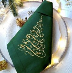 a green napkin with a gold christmas tree on it sitting on top of a white plate