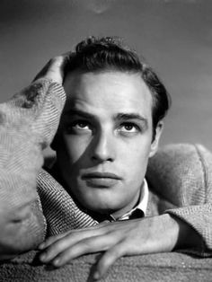 an old black and white photo of a man with his hands on his head, leaning against the back of a couch