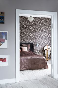 an open door leading to a bedroom with a bed and pictures on the wall behind it