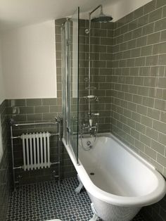 a white bath tub sitting next to a radiator in a bathroom under a window