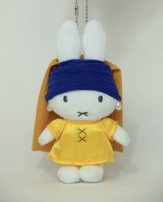 a white stuffed animal wearing a yellow shirt and blue bandanna on it's head