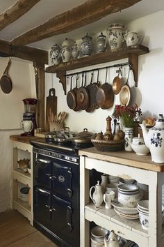 an old fashioned kitchen with pots and pans on the wall above the stove top