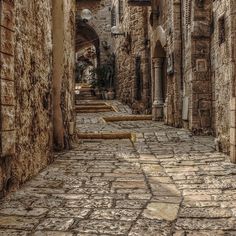 an alley way with stone walls and cobblestone flooring in the old city