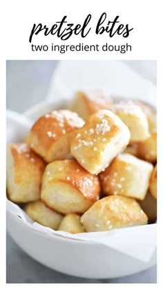 a white bowl filled with bread rolls covered in sesame seeds and sea salt on top of a gray surface