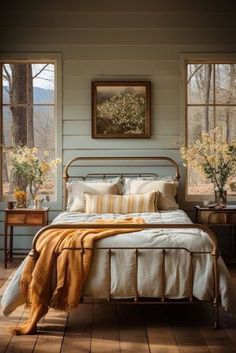 a bed sitting in a bedroom next to two tables with flowers on top of it