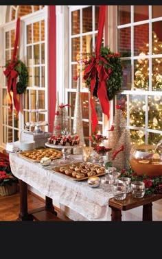 a table topped with lots of food next to a window covered in red ribbon bows