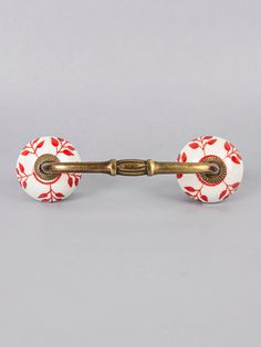 a pair of red and white flowered glass door knobs with brass pulls on a gray background