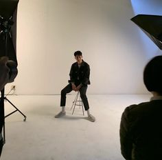 a man is sitting on a chair in front of a camera and lighting set up