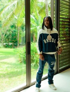 a young man standing in front of a window wearing a blue and white hoodie