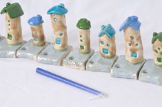 a row of little houses sitting on top of each other next to a blue pencil