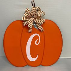 an orange pumpkin with the letter c on it and a bow hanging from it's front