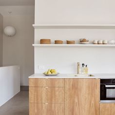 a kitchen with white walls and wooden cabinets, an oven and countertop area in the center