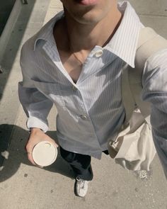 a man with sunglasses and a white shirt is holding a coffee cup in his right hand