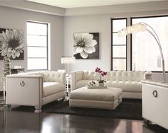 a living room with white furniture and large windows