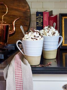 two mugs filled with ice cream sitting on top of a counter next to books