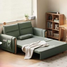 a living room with a couch, table and bookshelf next to it in front of a window