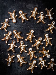 ginger cookies decorated with icing in the shape of skeletons on a black background, top view