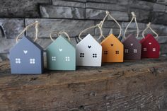 small wooden houses are lined up on a piece of driftwood with twine string