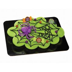 a cake decorated with green icing and spider webs on the top is sitting on a black plate